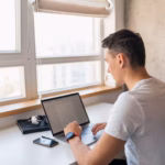 young-handsome-man-casual-outfit-sitting-table-working-laptop-freelancer-home_285396-1837